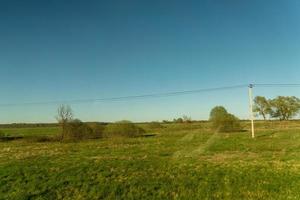 paisagem rural do final da primavera. campo verde e linha de energia ao longo da estrada. lado do país russo. foto