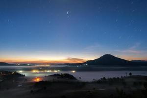 paisagem céu noturno com cauda de estrela e nevoeiro no nascer do sol da manhã em khao takhian ngo ponto de vista em khao-kho phetchabun, tailândia foto