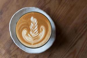 uma xícara de café com leite na mesa de madeira foto