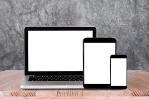 vista frontal do laptop, tablet pc, smartphone está na mesa de trabalho com fundo de concreto foto