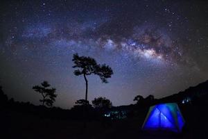 silhueta de árvore com tenda e via láctea no parque nacional de phu hin rong kla, phitsanulok tailândia. fotografia de longa exposição. foto