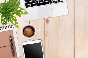 espaço de trabalho moderno com espaço de cópia de xícara de café, notebook e tablet laptop no fundo da mesa de madeira. vista do topo. estilo plano leigo. foto