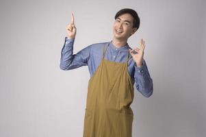 retrato de jovem asiático vestindo avental sobre o conceito de estúdio, culinária e empresário de fundo branco foto