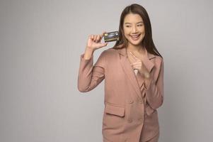 jovem mulher asiática segurando o cartão de crédito sobre o conceito de estúdio, compras e finanças de fundo branco. foto