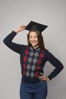 jovem mulher sorridente segurando o chapéu de formatura, educação e conceito universitário foto