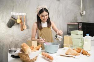 jovem mulher bonita está assando em seu negócio de cozinha, padaria e cafeteria foto