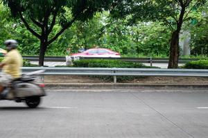 um homem na moto em movimento rápido, turva. passeio de motociclista ao longo da estrada na área urbana verde. foto