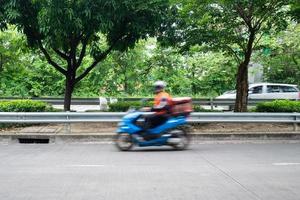 correio ou entregador na moto em movimento rápido, turva. courier realiza pedidos para entrega na área urbana. foto