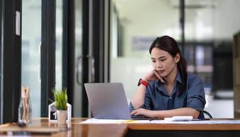 retrato de jovem asiática trabalhando no laptop no escritório foto