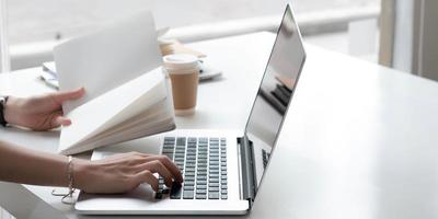 Feche a mão da empresária digitando no teclado do computador de um laptop no escritório. conceito de negócios e finanças. foto