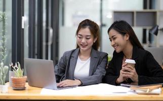 duas jovens empresárias asiáticas conversam, consultam, discutem o trabalho com a nova apresentação da ideia do projeto de inicialização analisam o plano de marketing e investimento no escritório. foto