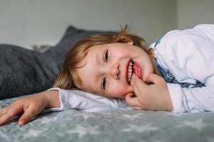 criança bonita está mentindo e se divertindo em casa no sofá, sorrindo e rindo foto