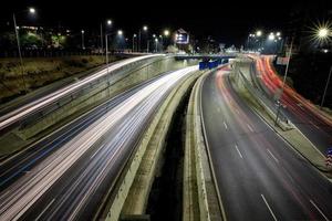 estrada de junção de tráfego noturno com luzes do movimento do veículo. visão horizontal foto