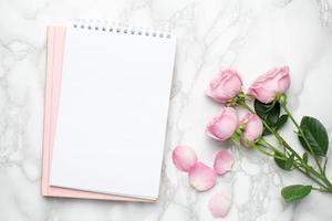 linda flor de rosas cor de rosa e notebook em mármore background.minimalistic composição para os feriados, dia dos namorados e dia das mulheres. foto