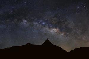 céu noturno estrelado com alta montanha e galáxia via láctea com estrelas e poeira espacial no universo foto