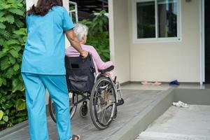 cuidador, ajuda e cuidado paciente idoso asiático ou idosa senhora sentada em uma cadeira de rodas na rampa de um hospital de enfermagem, conceito médico forte e saudável foto