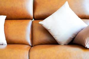 Almofada quadrada de cor clara no sofá de couro genuíno de luxo clássico vintage laranja marrom. foto