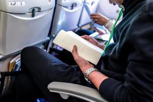 passageiro de atendimento leu o livro no assento do avião. foto