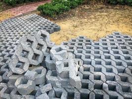 azulejo de bloco de tijolo de pedra de cor cinza com grama verde e areia como plano de fundo ou textura. foto