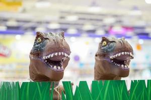 2 brinquedos modelo t-rex marrons saem da grama plástica na loja infantil, loja de departamentos de bangkok, tailândia. foto