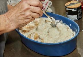 chef derrama molho bechamel, couve-flor em prato de cerâmica para assar no forno foto