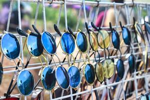 vários óculos de sol coloridos pendurados em um rack.different óculos de sol pendurados em um hanger.collection branco de óculos de sol no cabide. foto