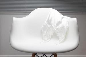 pijamas de cetim branco penduradas em uma cadeira foto