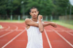 atletas esporte homem corredor vestindo roupas esportivas brancas para alongamento e aquecimento antes de praticar em uma pista de corrida em um estádio. conceito de esporte de corredor. foto