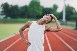 atletas esporte homem corredor vestindo roupas esportivas brancas para alongamento e aquecimento antes de praticar em uma pista de corrida em um estádio. conceito de esporte de corredor. foto