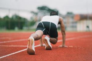 atletas esporte homem corredor vestindo roupas esportivas brancas para alongamento e aquecimento antes de praticar em uma pista de corrida em um estádio. conceito de esporte de corredor. foto