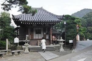 uma senhora rezando no antigo pequeno santuário japonês foto