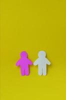 duas silhuetas de um povo esculpido em papel branco e rosa sobre fundo amarelo. conceito de comunicação, relacionamentos, amor, trabalho em equipe foto