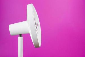 ventilador elétrico moderno branco para resfriar a sala em um fundo rosa. foto
