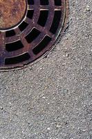 escotilha redonda de esgoto com uma grelha em uma estrada de asfalto. foto