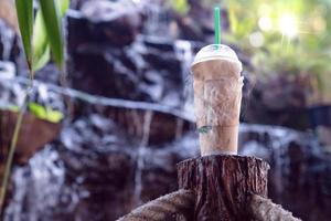 café gelado em copo de plástico e vapor no poste com fundo desfocado de cachoeira foto