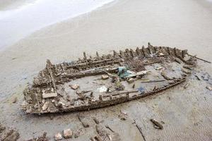velho barco de madeira abandonado na praia foto