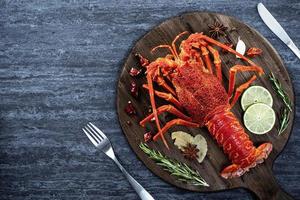 lagosta cozida cozida, deliciosa refeição de frutos do mar jantar com faca e garfo em fundo de ardósia de pedra preta, design de menu de restaurante, vista superior, sobrecarga foto