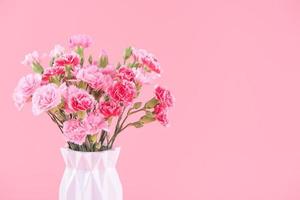 conceito de design de presente de feriado do dia das mães, buquê de flores de cravo rosa com cartão, isolado em fundo rosa claro, espaço de cópia. foto