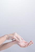 Lavando as mãos. jovem asiática usando sabão líquido para lavar as mãos, conceito de higiene para proteger o coronavírus pandêmico isolado em fundo branco cinza, close-up. foto