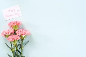 fundo do dia das mães, bando de cravos - lindo buquê de flores rosa pálido isolado na mesa azul pastel, vista superior, configuração plana, design de espaço de cópia. foto