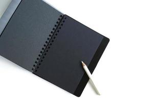 caderno espiral de papel preto e lápis branco foto