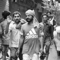 velha delhi, índia, 15 de abril de 2022 - grupo não identificado de homens andando pelas ruas da velha delhi, fotografia de rua do mercado chandni chowk da velha delhi durante a manhã, velha delhi street photography foto