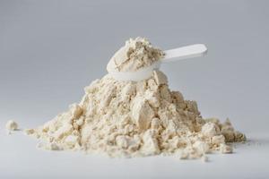 uma montanha de proteína de soja isolada em pó com uma colher de medição em um fundo branco. foto