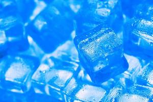 cubos de gelo com gotas de água espalhadas sobre um fundo azul, vista superior.