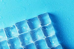 gelo feito de cubos alinhados com gotas em um fundo azul com espaço livre foto