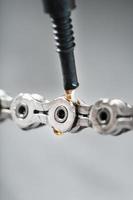 lubrificar uma corrente de bicicleta com uma gota de óleo dourado close-up em um fundo cinza foto
