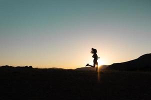 garota corre ao pôr do sol nas montanhas. foto