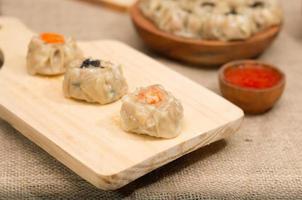 dimsum cozinhado chinês ou dim sum, na placa de madeira, cozinha tradicional foto