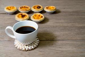 café com torta de ovo em copo de papel alumínio na mesa de madeira foto