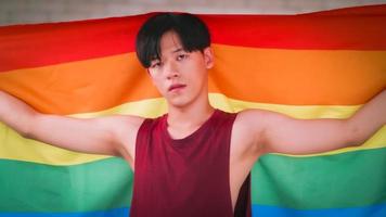 retrato de homem gay asiático segurando uma bandeira de arco-íris. foto